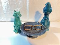 Group shot of all four items: fox figurine, bird figurine, blue pedestal dish, metal eyeglasses