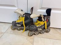 Pair of Bauer inline hockey skates on floor showing overall condition