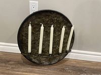 Front view of round metal sconce with five taper candles inserted