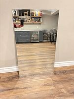 Full view of frameless rectangular mirror leaning against wall, showing clear reflective surface and polished edges