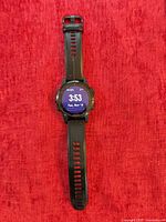 Front view of Garmin Fenix 5S Plus smartwatch with band extended on red background