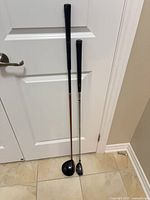 Both golf clubs leaning against door showing full length