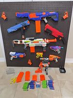Full lot view showing ten blasters mounted on pegboard with accessories on floor