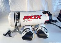 Punching bag lying sideways with gloves, chain, swivel and bracket visible