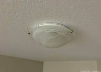 Fixture installed on ceiling showing frosted dome and brushed nickel clips