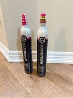 Two SodaStream aluminum CO₂ cylinders standing upright