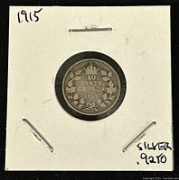1915 Canadian 10 cents silver coin reverse, displaying denomination and wreath design, mounted in white cardboard holder with handwritten notes.