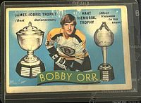 Front side of the Bobby Orr hockey card showing his image with James Norris Trophy and Hart Memorial Trophy illustrations.