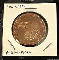 Obverse side of the 1 oz copper round showing eagle head design and handwritten notes indicating 1 oz copper and BU condition.