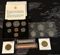 Photo of 1974 PL set coins in display box, 1987 proof loonie, graded 1988 PL66 coin, and rolls of 2002 1 cent and 10 cent coins.