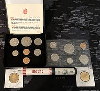 1976 Canadian coin set in a black presentation box with printed insert and protective sleeves containing various coins including a large silver dollar and pennies.