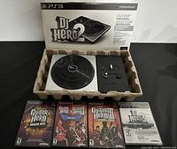 The full lot displaying the PS3 DJ Hero 2 turntable controller in its box alongside four video games, three for PlayStation 2 and one for PS3