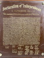 Close-up of the laser etched Declaration of Independence text and signatures on composite board revealing gold-colored lettering and scuff marks.