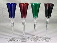 Front view of all four crystal champagne flutes showing blue, ruby red, green, and amethyst colors.