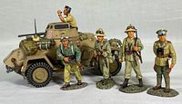 Five Afrikakorps troops standing in front of an armored assault vehicle painted with desert camouflage. Figures are highly detailed and scale matched to vehicle.