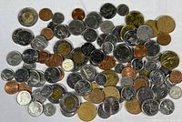 Top view showing a variety of Canadian coins in different denominations and conditions spread out on a white surface.
