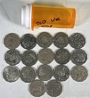 Coins laid out on a flat surface with an orange pill bottle labeled 'OLD UK 50P'. Mostly UK 50 pence coins with some Australian 50 cent pieces visible.