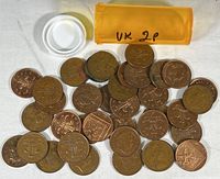 Coins spread around with plastic coin tube lid removed showing various 2 pence coins and tube labeled 'UK 2P'