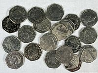 Photo showing multiple United Kingdom 50 pence coins with Queen Elizabeth II profile and varying reverse designs spread on a white surface.