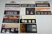 Photo of all ten mint stamp sets in original packaging laid out together, showing various themes and conditions.