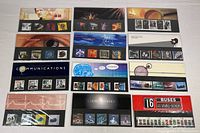 Twelve complete sets of Royal Mail mint stamps in original packaging, laid out for display showing different series and themes.