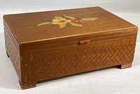 Closed wood jewelry box with hand painted yellow and red flowers on lid, visible basketweave carved pattern on the sides, and small Bakelite tab on front.