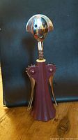 Photo of Alessi Anna G. corkscrew with distinctive smiling face design, gold metal head and burgundy plastic body.