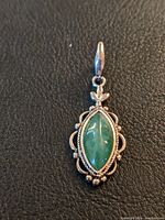Close-up front view of jade and silver pendant showing green marquise-shaped jade stone and silver ornate frame.