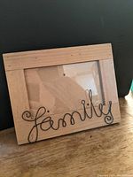 Front view of a wooden photo frame with wire word 'family' on the bottom.