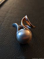 Close-up of the pearl ring showing the round pearl set in a curling sterling silver band.