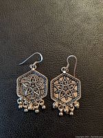 Front view of handmade sterling silver hexagonal earrings showing detailed floral design and dangling beads.