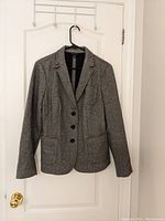Front view of Talbot's women's grey blazer hanging on black hanger showing button front and patch pockets.