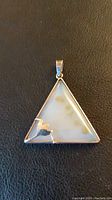 Photo of triangle-shaped pendant with a silver-tone frame and a triangular polished stone center.