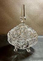 Front view of the covered crystal candy dish showing intricate cut patterns, three feet, and the lid with tall handle.