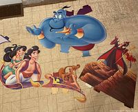 Photo showing Genie, Aladdin on magic carpet with Jasmine, Abu and Iago standup character cutouts arranged on floor.