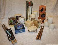 Lot of various candles including colorful glass votive candles, square and round decorative candles, Halloween themed candles, tapers and Ronson Varaflame metal gas candles.