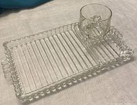 Close-up of one glass snack tray with matching glass beverage cup placed in integrated slot on the tray edge.