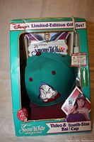 Front view of the Disney Snow White Limited Edition gift set box showing the youth-sized baseball cap with Grumpy embroidered and the Snow White video cassette behind it.