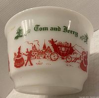 Side view of milk glass punch bowl showing Tom and Jerry text and vintage red and green illustrations.