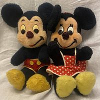 Front view of vintage Mickey and Minnie Mouse plush stuffed characters sitting side by side on a white fabric background.