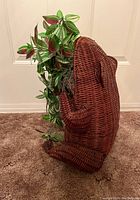 Side view of the woven wicker frog planter with artificial plant inside.