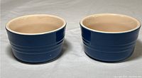 Photo showing two indigo blue Le Creuset ramekins side by side on a gray surface.