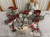 Overview of assorted Christmas ornaments and decorations laid out, including baubles, string lights, candle holders, and figurines.