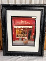 Full view of framed photography print showing French wine shop storefront with black frame and white mat.