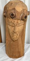 Front view of the wooden Christ head sculpture showing detailed facial features and faceted carving style.