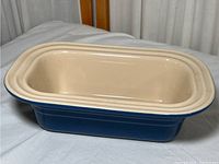 Blue stoneware bread loaf pan with cream interior viewed at an angle showing overall exterior and interior.