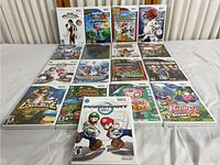 Photo showing a collection of 15 Nintendo Wii game cases arranged in five rows of three on a white surface including titles like Tomb Raider Anniversary, Super Mario Galaxy 2, and Kirby's Dream Land.
