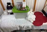 Full overview of the Christmas collection items displayed including the snowman figurine, storage container with green lid, decorative greenery, white snowflake mats, red placemats, white gloves, and white ceramic lantern.