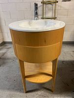 Full front view of the vanity sink showing wood base and white ceramic basin with installed faucet.
