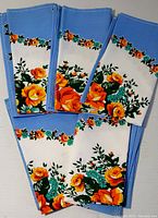 Photo showing five folded vintage floral dinner napkins with a blue edges and a colorful floral print.